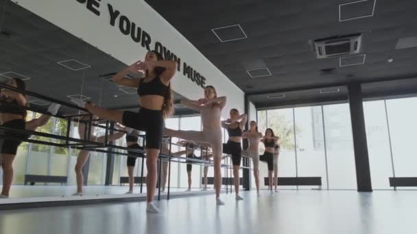 Grupo de mujeres flexibles entrenando juntas en la barra, practicando ejercicio de estiramiento de ballet en el estudio de danza, rastreando disparos — Vídeos de Stock