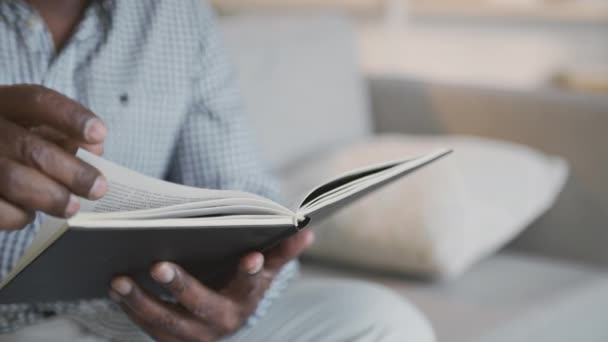 Agygyakorlat. Felismerhetetlen afro-amerikai férfi könyvet olvas, otthon pihen a kanapén, nyomkövető lövés. — Stock videók