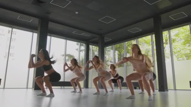 给年轻女士上健身课一群年轻的女运动员和教练一起运动，一起练习跳腿 — 图库视频影像