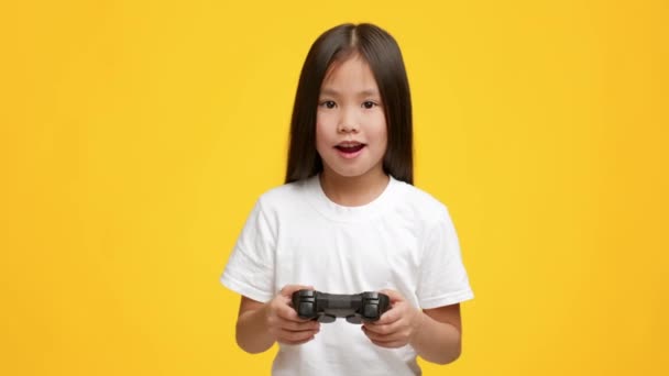 Asiática chica jugando video juego tener divertido sobre amarillo fondo — Vídeos de Stock