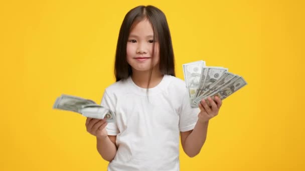 Menina japonesa feliz segurando dinheiro em dinheiro sobre fundo amarelo — Vídeo de Stock