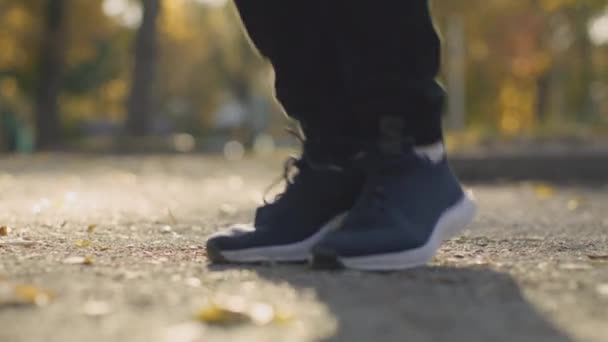 Kardioträning. Närbild skott av manliga ben bär sportiga sneakers hoppa utomhus i parken på morgonen, slow motion — Stockvideo