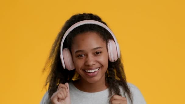 Black Girl Listening Music In Headphones And Dancing, Yellow Background — Stock Video