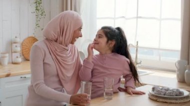 Müslüman anne ve kızı evde somurtarak eğleniyor.