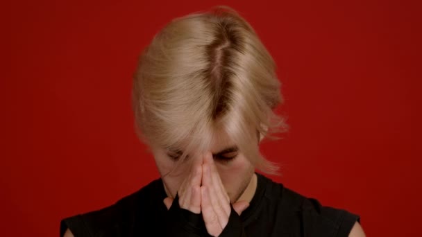 Close-up portret van geconcentreerde jonge kickboxer ademhaling en bidden, op zoek slordig op camera, rode achtergrond — Stockvideo