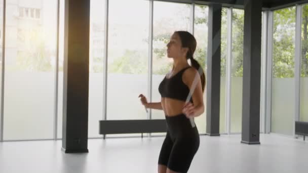 Kardio edzés. Fiatal nő sport ruha ugró kötél, gyakorló egyedül fényes fitness stúdió — Stock videók
