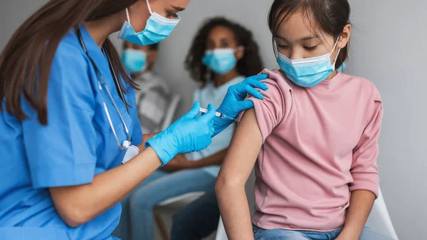 Verpleegster maken Covid-19 Vaccin Injectie naar aziatisch meisje binnen, Panorama — Stockfoto