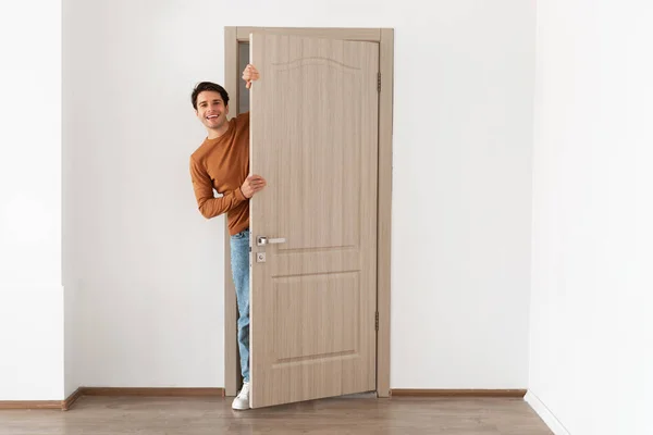 Vrolijke kerel kijkt uit de deur staan in de deuropening — Stockfoto
