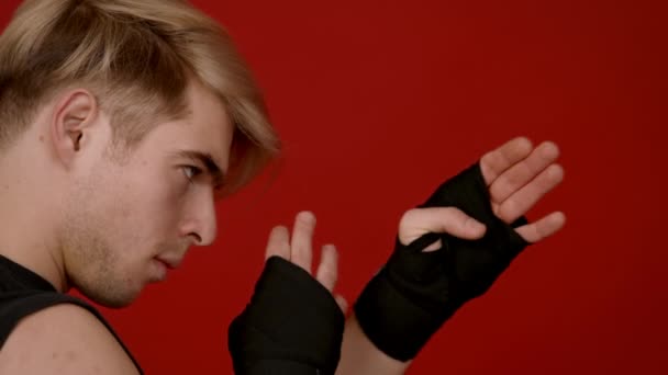 Ready to fight. Profile portrait of young furious kickboxing fighter raising hand wrapped in gloves in attack position — Stock Video