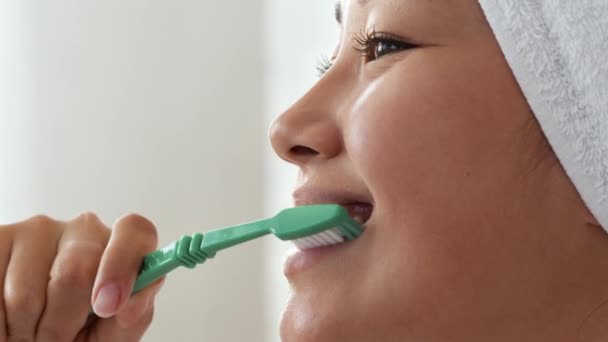 Hábitos de higiene dental. Joven positivo asiático mujer cepillarse los dientes con cepillo de dientes después de la ducha de la mañana, de cerca — Vídeos de Stock