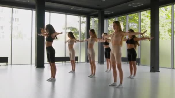 Tanzkurse. Gruppe junger schlanker, flexibler Damen übt neuen Tanz im Studio, bewegt sich gleichzeitig mit Trainer, Kamerafahrt, Zeitlupe — Stockvideo