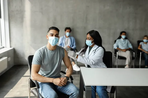 Hombre musulmán recibiendo inyección intramuscular contra el coronavirus en el lugar de vacunación —  Fotos de Stock