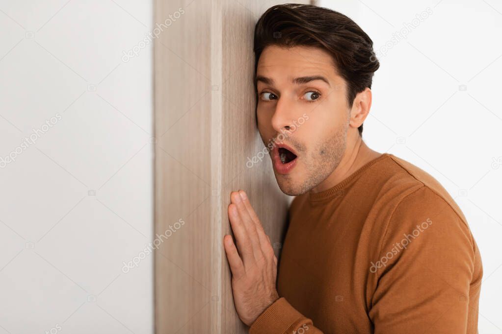 Shocked young guy listening through the door