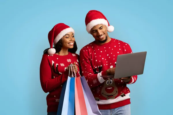 Leende svarta shopaholics njuter julförsäljning, med hjälp av laptop — Stockfoto