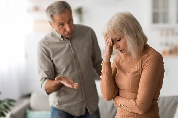 Vzteklý starší manžel křičí na nešťastnou ženu, která má konflikt uvnitř — Stock fotografie