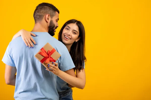 Romantik Arap kadının kocasını kucaklaması, kameraya hazır olması ve gülümsemesi, sarı arka planda poz vermesi, boş alan. — Stok fotoğraf