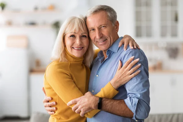 Loving Senior Couple Embracing Smiling To Camera At Home — Stock Photo, Image