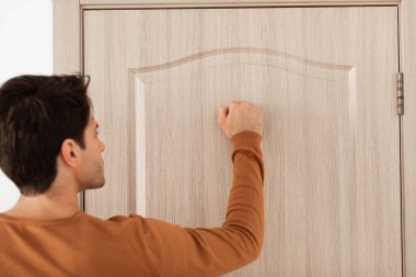 Ahşap kapıyı çalan adama yakın çekim.