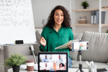 Genç öğretmen çevrimiçi matematiği açıklıyor. Video çağrısı yapıyor.