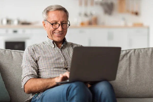 Boldog Senior Man használata Laptop böngészés Internet Ülés otthon — Stock Fotó
