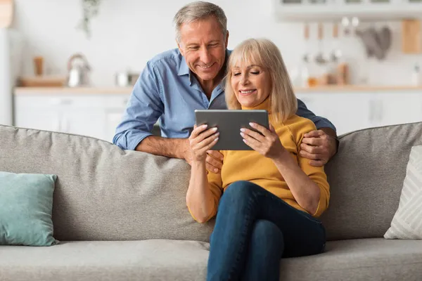 Gelukkig senior paar met behulp van digitale tablet surfen op internet thuis — Stockfoto