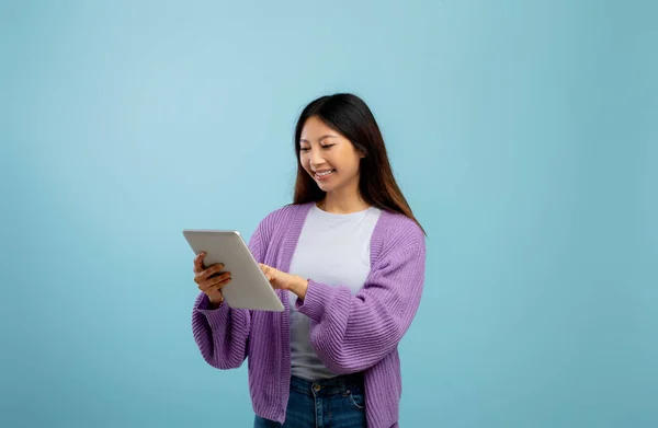 Çevrimiçi hayat. Uzak eğitim için tablet bilgisayar kullanan Asyalı kadın mavi stüdyo geçmişinin başında duruyor. — Stok fotoğraf