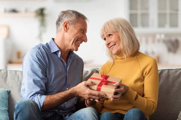 Старший чоловік дарує подарунок дружині святкування річниці вдома — стокове фото