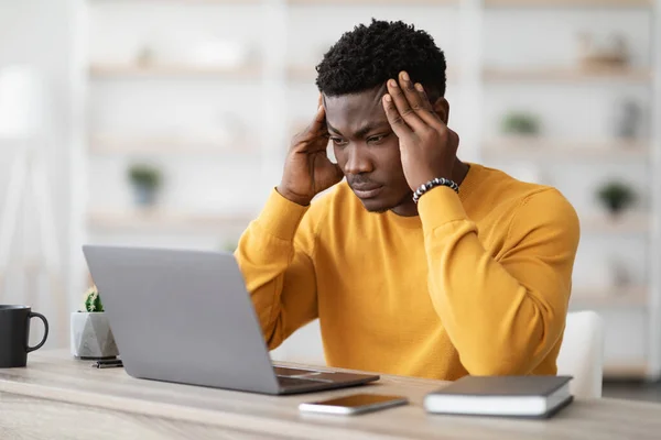 Gerente afroamericano estresado trabajando en el ordenador portátil, tocando la cabeza —  Fotos de Stock