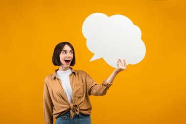 Çılgınca. Duygusuz kadın elinde boş bir konuşma balonu tutuyor ve heyecanla bağırıyor, turuncu arka plan, serbest alan