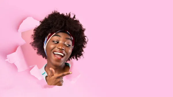 Feliz alegre jovem senhora afro-americana bonita com boca aberta olhar através de buraco em papel rosa — Fotografia de Stock