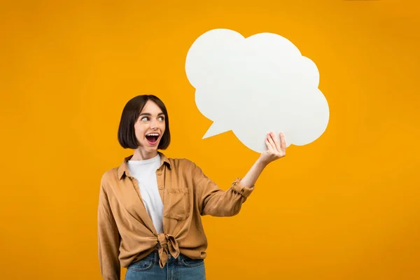 Crazy idea. Emotional lady holding blank speech bubble and exclaiming with excitement, orange background, free space — Stock Photo, Image