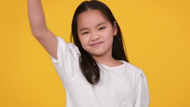 Não gosto de gestos. Pouco asiático menina gesto polegar para baixo e sacudindo cabeça não, expressando negação, laranja estúdio fundo — Vídeo de Stock