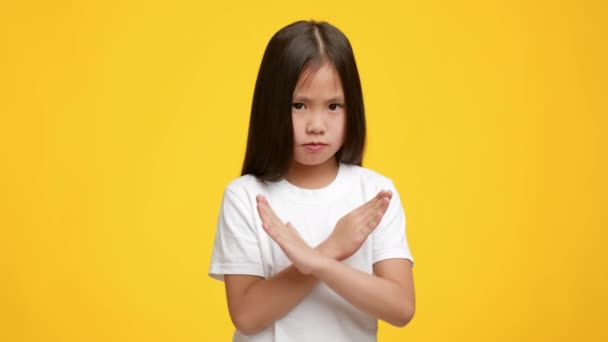 Serio asiático chico chica gestos dejar de cruzar manos, fondo amarillo — Vídeos de Stock