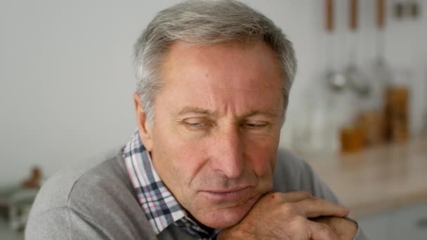 Close-up van Pensive Senior Man zit in de keuken thuis, op zoek weg — Stockvideo
