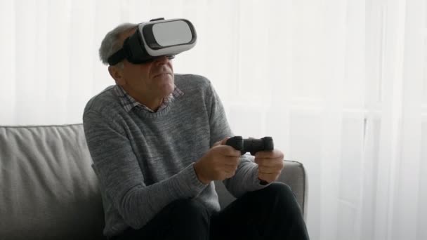 Homem Sênior excitado usando fone de ouvido VR jogando videogames em casa — Vídeo de Stock