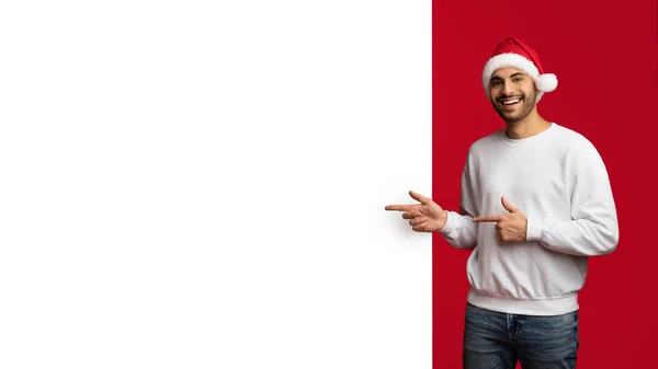 Alegre árabe chico en santa sombrero señalando en blanco publicidad Junta — Foto de Stock