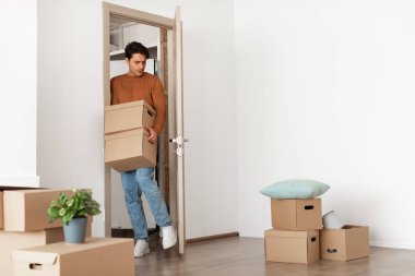 Elinde karton kutular olan adam, yeni eve giriyor.