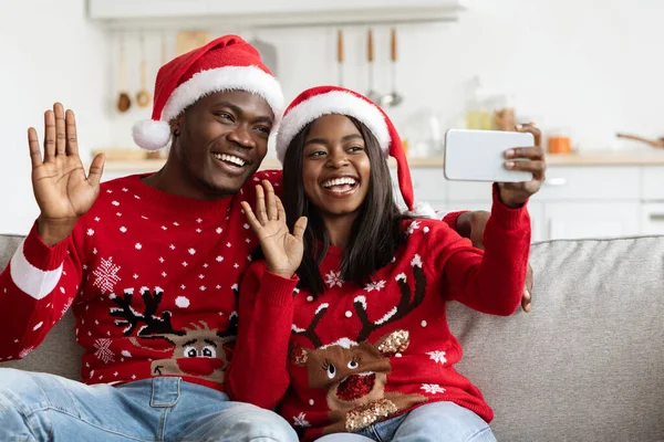 Vackra svarta älskare i Santa hattar vinka på smartphone-skärmen — Stockfoto