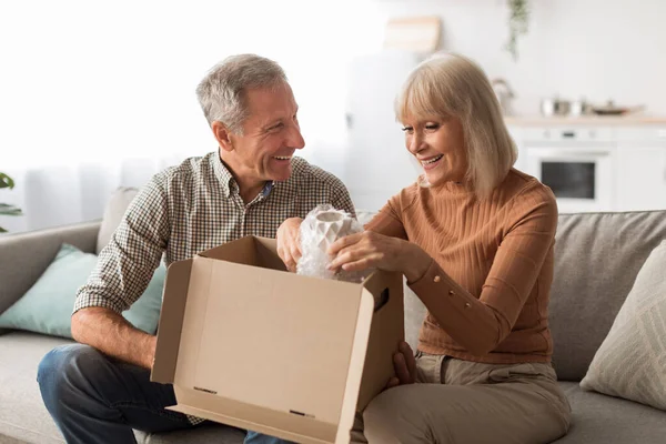 Ευτυχισμένο ώριμο ζευγάρι ξεπακετάρισμα κουτί μετά την επιτυχή ψώνια στο σπίτι — Φωτογραφία Αρχείου