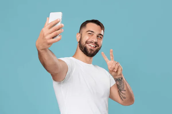 Glückliche reife kaukasische Mann macht Videoanruf auf Smartphone und zeigt Friedenszeichen auf Webcam — Stockfoto