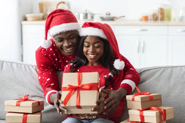 Χαμογελώντας αφροαμερικανό ζευγάρι ανοίγοντας χριστουγεννιάτικα δώρα από συγγενείς — Φωτογραφία Αρχείου