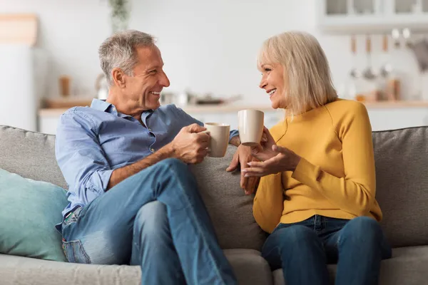 Veselý starší pár pití čaje a mluvení sedí doma — Stock fotografie