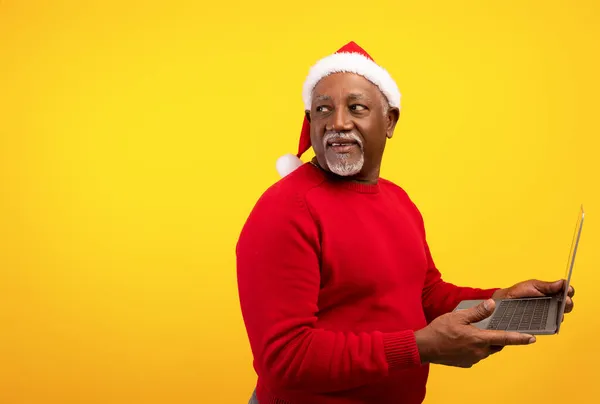Hombre negro mayor usando el ordenador portátil para las compras de Navidad, mirando por encima de su hombro en el espacio vacío para el anuncio de vacaciones — Foto de Stock