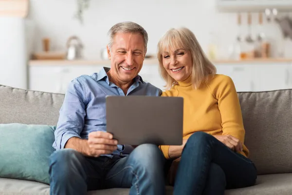 Šťastný starší pár pomocí notebooku procházení Internetu společně doma — Stock fotografie