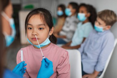 Klinikte oturan Asyalı Ergen Kız Covid-19 testi yaptırıyor.