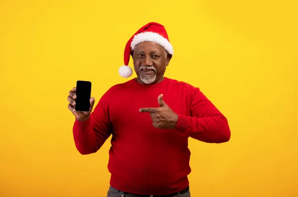 Feliz hombre negro senior en Santa sombrero apuntando al teléfono inteligente con maqueta para la aplicación de compras de Navidad o sitio web de la tienda de Internet — Foto de Stock