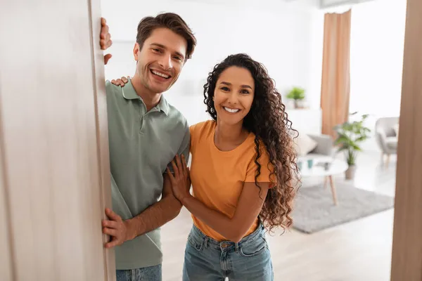 Happy young couple inviting people to enter home — Stok Foto