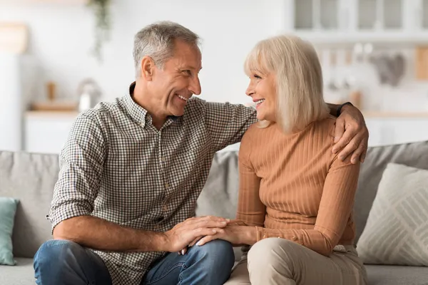 Glückliches Seniorenpaar im Gespräch Umarmung im Sitzen auf Sofa zu Hause — Stockfoto