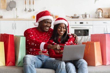 Gülümseyen siyah aşıklar online alışveriş yapıyor, Noel tekliflerinin tadını çıkarıyor.