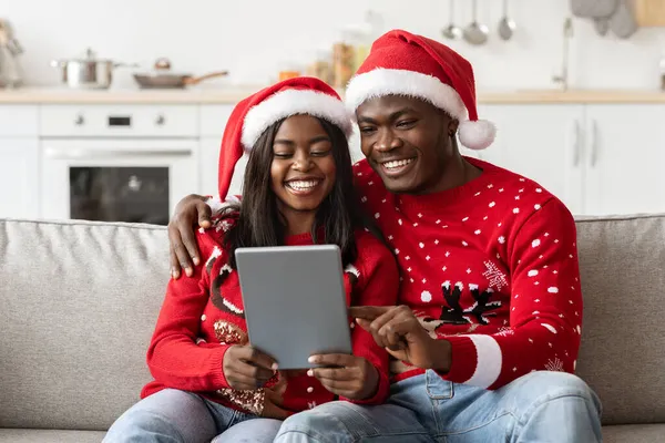 Positivt svart par sitter på soffan, med hjälp av digital tablett — Stockfoto